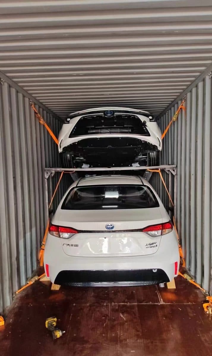 Two vehicles loaded on a double-deck rack inside a 40-foot high-cube container